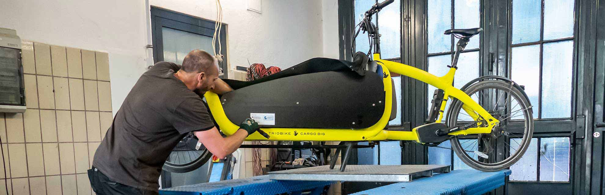 Fahrradtechniker schraubt in seiner Werkstatt an einem Cargobike